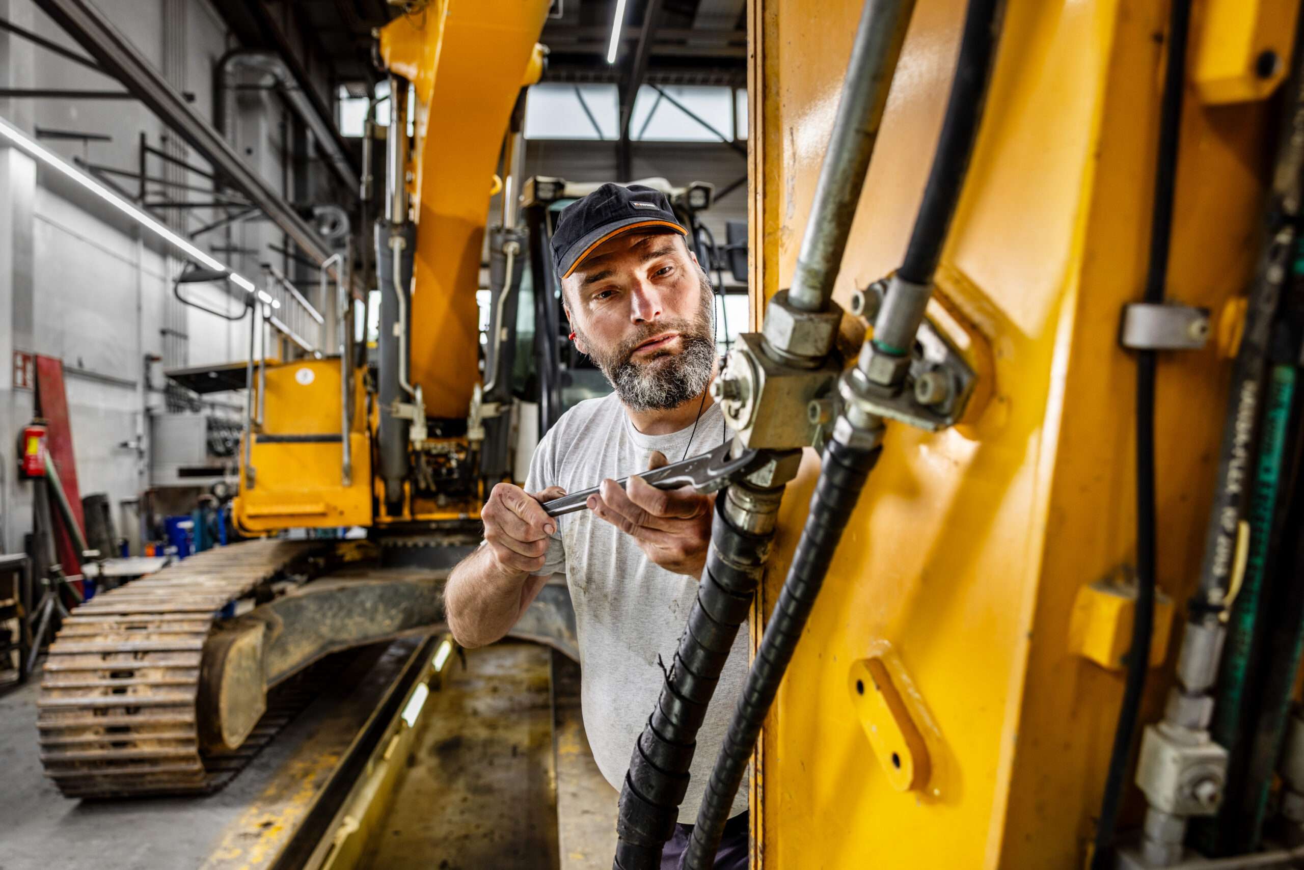Mechatroniker beim Reparieren eines Hydraulikschlauchs