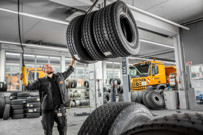 Mitarbeiter holt Reifen für ein LKW aus dem Lager